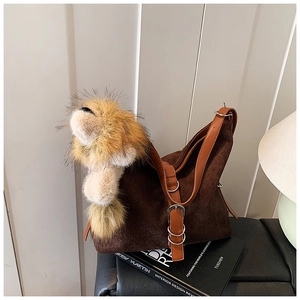 Close-up of woven shoulder bag texture with brown leather strap and lion plush charm