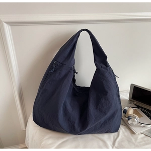 Détails d'un sac hobo en nylon bleu foncé avec large bandoulière et fermeture éclair