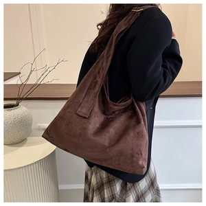 Vue macro du sac hobo en daim marron foncé avec large bandoulière dans un décor épuré