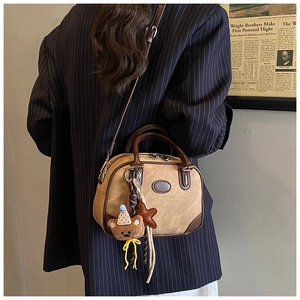 Detail of vintage patchwork boston bag with suede texture and bear charm accessory