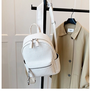 Detail of cream woven backpack texture and metal zipper pockets on a stylish daypack