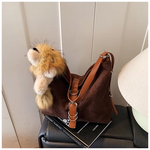 Detail of deep brown woven hobo bag featuring a cute lion plush pendant on leather strap