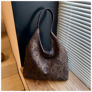 Detail of paisley canvas tote bag with brown leather straps on a wooden step