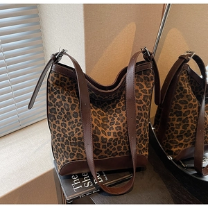 Detail of leopard print hobo bag with brown leather trim resting on a lifestyle prop