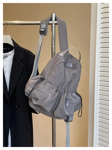 Close-up of lightweight grey nylon backpack featuring external zippers and drawstring detail