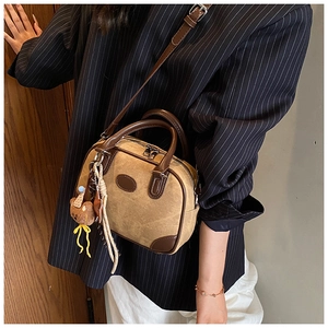 Detail of vintage canvas and leather patchwork handbag with bear charm and woven strap