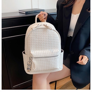 White woven faux leather backpack with silver zippers and a cute metal bear charm