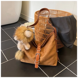 Close-up of brown woven bucket bag featuring a decorative lion plush charm and leather strap