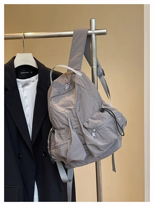 Detail view of grey nylon backpack with side bungee cords and multiple zip pockets
