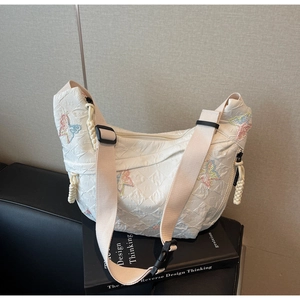 Detail of colorful butterfly embroidery and woven zipper pulls on white canvas bag