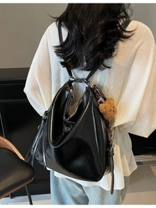 Versatile black glossy leather bucket bag with contrast stitching and bear charm accessory