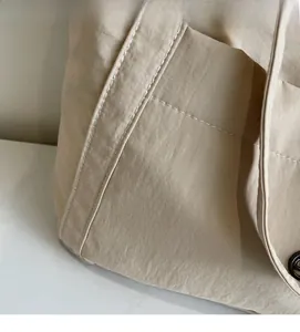 Close-up of beige canvas tote bag fabric showing fine natural texture and neat double stitching