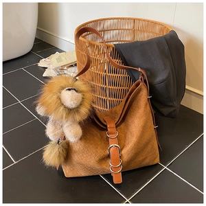 Close-up of caramel suede leather woven bucket bag with lion plush pendant and buckle