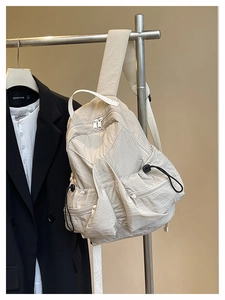 Detail of cream casual backpack showing crinkled nylon texture and side drawstring pocket