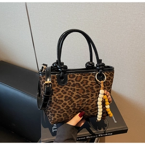 Dettaglio macro della borsa leopardata con nappa di perline e manici in pelle nera