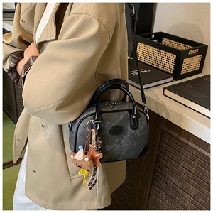 Close-up of retro dark grey textured crossbody bag with a cute teddy bear charm pendant