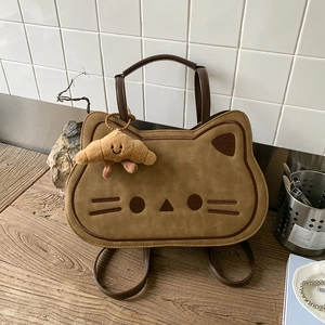 Close-up of cat-shaped brown backpack with plush croissant charm and embroidery