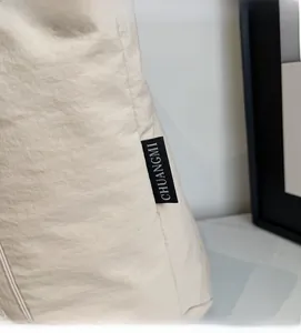 Detail of beige canvas tote bag material with CHUANGMI woven brand label and stitching