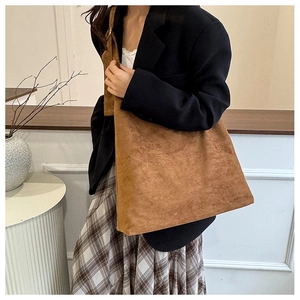 Détail d'un grand sac à bandoulière en daim marron au style vintage pour l'automne