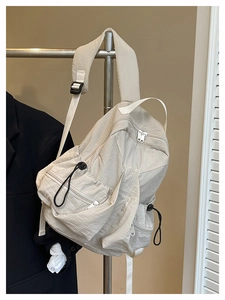 Detail view of light beige nylon backpack with textured grid fabric and zipper pockets
