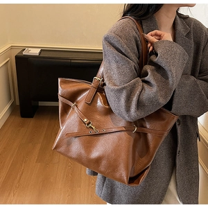 Detail view of vintage brown tote bag with glossy leather texture and golden metal buckle