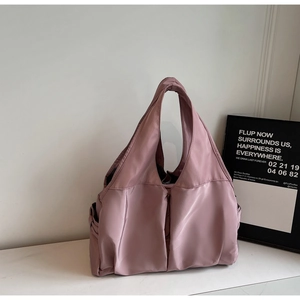 Vue détaillée du sac cabas rose en nylon montrant la poche latérale et la texture