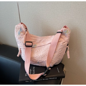 Detail of pink canvas bag featuring butterfly embroidery and diamond pattern texture