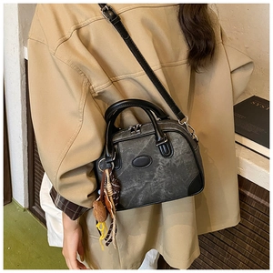 Detail showing deep gray textured Boston bag with leather handles and decorative charm