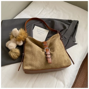 Detail of brown suede hobo bag featuring woven texture and decorative plush lion charm