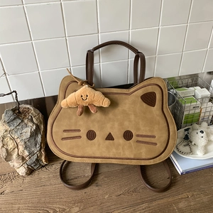 Detail of cute cat-shaped brown suede handbag with croissant plush charm and fine stitching