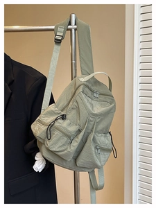 Detail view of olive green nylon sports backpack with multiple zipper pockets and drawstrings