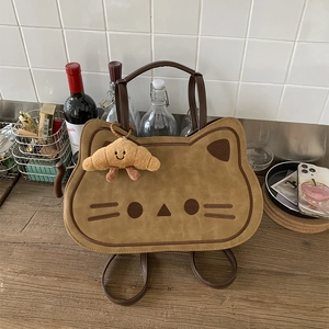 Close-up of cat-shaped backpack with soft suede texture and a smiling croissant charm