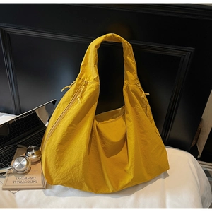 Détail du sac bandoulière en nylon jaune avec texture plissée et large bandoulière
