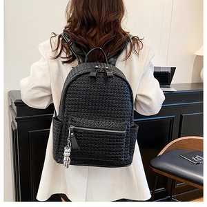 Detail view of black woven leather backpack with silver zippers and cute bear charm