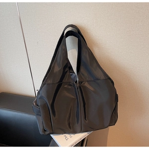 Détail d'un grand sac cabas en nylon noir avec bandoulière large et poches latérales