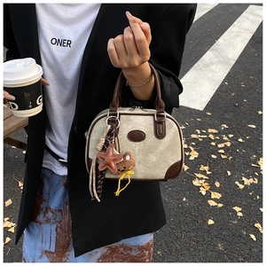 Detail of canvas and leather boston bag with bear charm and star pendant accessory
