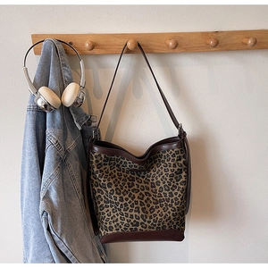 Detail of leopard print bucket bag with brown leather trim and shoulder strap on a hook