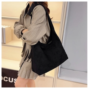 Détail d'un grand sac hobo en daim noir porté par un mannequin dans un style épuré