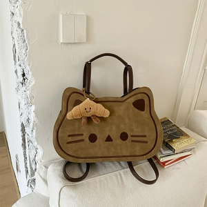 Detail of cute cat shaped brown shoulder bag with a small croissant plush charm