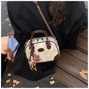 Rear view of a model wearing the two-tone Boston bag on a bench with autumn leaves