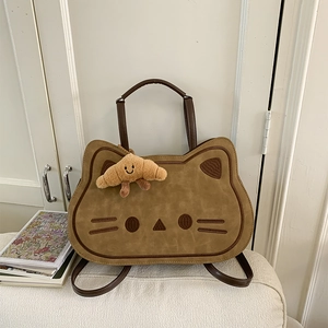Detail of a brown cat-shaped bag with suede texture and a cute croissant plush charm
