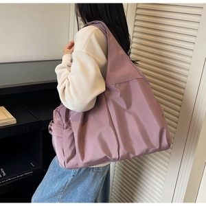 Gros plan sur la large bandoulière et le pli latéral d'un grand cabas en nylon violet