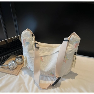 Detail of white quilted crescent bag with colorful butterfly embroidery and woven strap