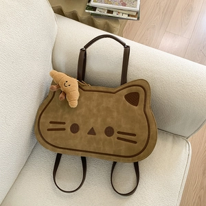 Detailed close-up of a khaki cat-shaped backpack with a plush croissant charm on a sofa