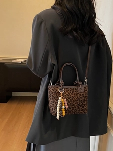 Mini borsa a secchiello leopardata con manici in pelle e ciondolo di perline colorate su modella