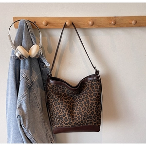 Leopard print canvas tote bag styled with denim jacket and headphones on wooden hook