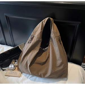 Détail du grand sac cabas en nylon marron montrant la texture plissée et le zip latéral