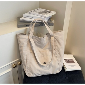 Close-up of minimalist beige canvas tote bag showing magnetic closure and outer pocket