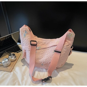Close-up of pink quilted canvas bag featuring colorful butterfly embroidery and wide strap