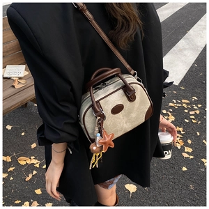 Close-up of a vintage beige canvas and brown leather mini bowling bag in an outdoor setting